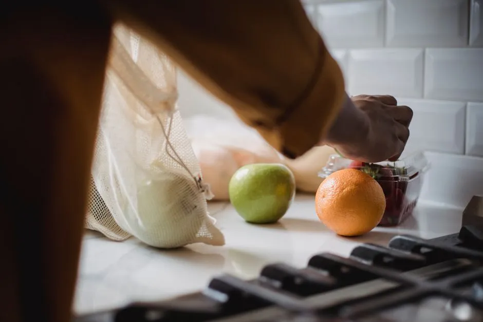 Person unpacking fresh fruit and vegetables onto a kitchen counter after a grocery trip