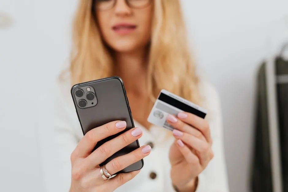 Person holding a smartphone in one hand and a payment card in the other