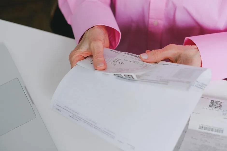 Person holding and reviewing a long paper receipt at a desk